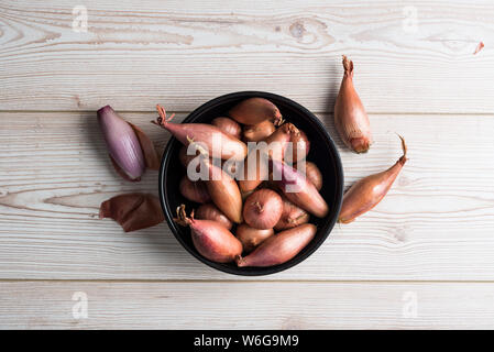 Banana and round shallots in a dark bowl on wooden surface Stock Photo