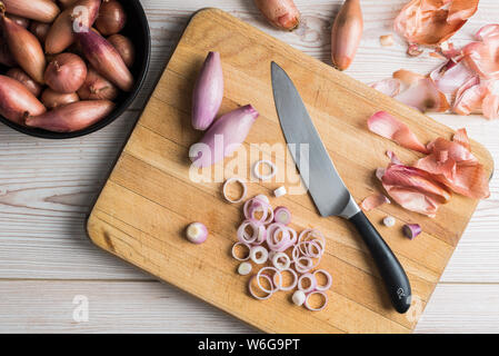 Banana and round shallots on a chopping board with a knife Stock Photo