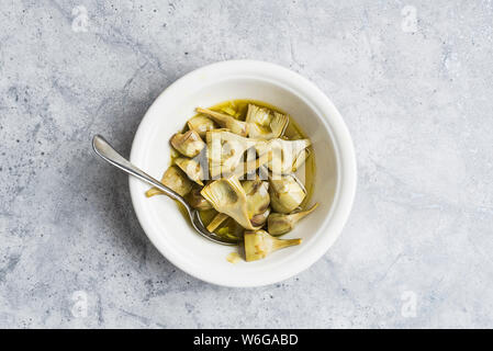 Bowl of cooked baby artichokes on a marble background Stock Photo