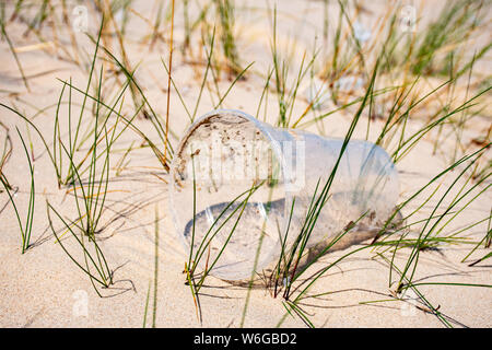 Rubbish plastic disposable cup on sandy beach, plastic pollution Stock Photo