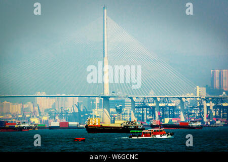 Scenic view of Tsing Ma Bridge in Hong Kong.  Numerous cargo vessels with freight containers. Cityscape of Hong Kong Stock Photo