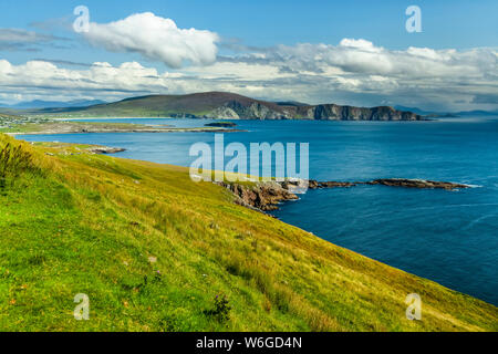 Bright blue water and lush green grass along the coastline of Achill Island on the Wild Atlantic Way; Achill Island, County Mayo, Ireland Stock Photo
