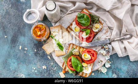 Toasts with cheese, fresh tomatoes, basil leaves and quail eggs. Tasty and healthy breakfast concept. Food banner Stock Photo