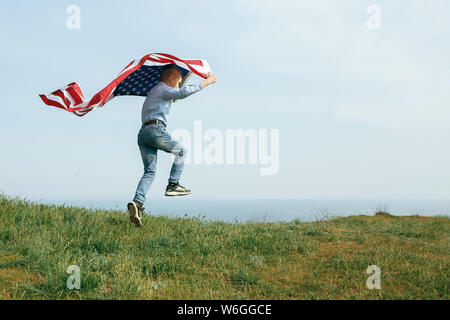 A little boy runs with the flag of the United States. July 4th Independence Day. Stock Photo