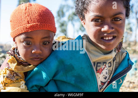 Ethiopian girl carrying a little boy, Simien Mountains; Amhara Region, Ethiopia Stock Photo