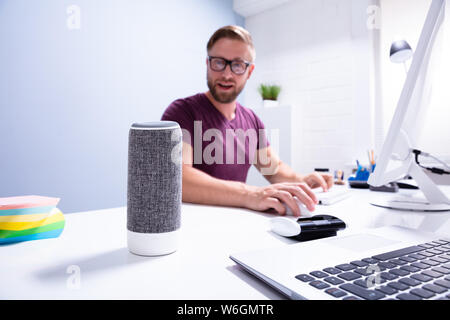 Young Man Working In Office Looking At Wireless Speaker Stock Photo