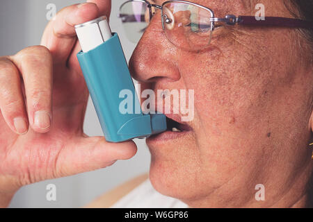Old woman using asthma inhaler. Asthma Treatment, Elderly Person Stock Photo
