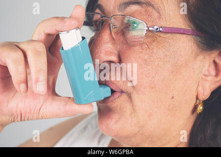 Old woman using asthma inhaler. Asthma Treatment, Elderly Person Stock Photo