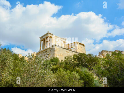 A well preserved area of the Parthenon on Acropolis Hill rises above the brush and trees in ancient Athens Greece.