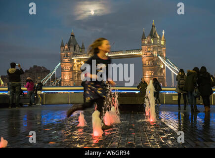 City Hall, South Bank, London, UK. 23rd December, 2015. Children dart in and out of the water feature next to City Hall in London with Tower Bridge in Stock Photo