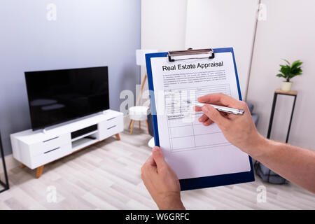 Close-up Of A Person's Hand Filling Real Estate Appraisal Form With Pen Stock Photo