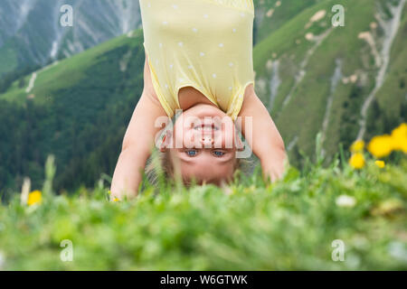 Little Girl Standing On Her Head In Mountains Stock Photo