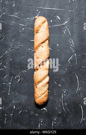 Fresh french baguette against a dark background. Long bakery bread made from flour, wheat and dough. Delicious healthy food for breakfast or dinner. Stock Photo