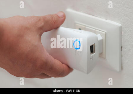 Man insert a wifi repeater in a wall plug Stock Photo