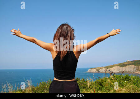 Young girl raising her arms on top of a mountain. Stock Photo
