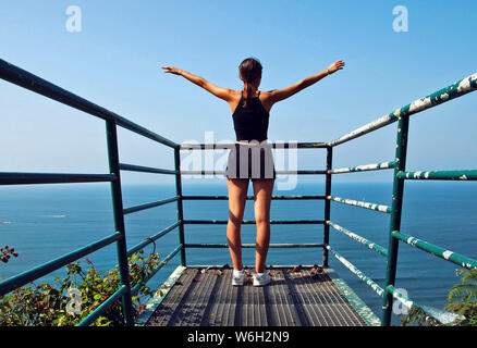 Young girl raising her arms on top of a mountain. Stock Photo