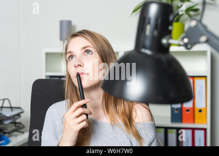 A young woman in the office is lost in thought Stock Photo