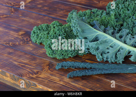 Popular kale varieties, Blue Curled Vates Kale end  Tuscan kale. Fresh juicy leaves of kale cabbage lie on a wooden table. Stock Photo