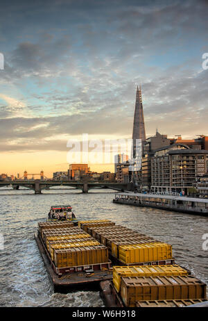 tug boat pulling cargo barge at thames river during evening Stock Photo