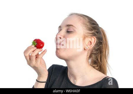 A young woman holds a strawberry and wants to it it Stock Photo