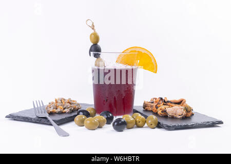 Traditional spanish appetizer. A glass of vermouth decorated with olives, and assorted tapas. Stock Photo