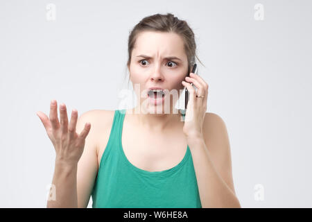 Woman complaining while talking on smartphone, confused and puzzled expression. Stock Photo