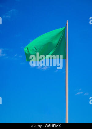 Green flag isolated waving on the sky Stock Photo