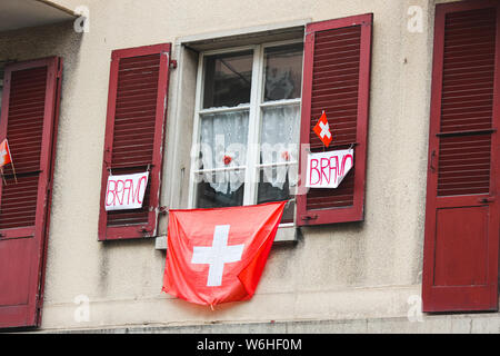 Decoration on a building on Swiss National Day. National holiday of Switzerland, set on 1st August. Celebration of founding of Swiss Confederacy. Independence. Swiss flags and sign saying bravo. Stock Photo
