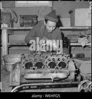 Heart Mountain Relocation Center, Heart Mountain, Wyoming. A young mechanic of Japanese ancestry, a . . .; Scope and content:  The full caption for this photograph reads: Heart Mountain Relocation Center, Heart Mountain, Wyoming. A young mechanic of Japanese ancestry, a resident at the Heart Mountain Relocation Center, honing cylinders in a truck motor. Motor equipment at the center consists of well used former Civilian Conservation Corps and Forestry Service trucks, and cars require considerable reconstruction and maintenance, which is performed by experienced resident mechanics and student w Stock Photo