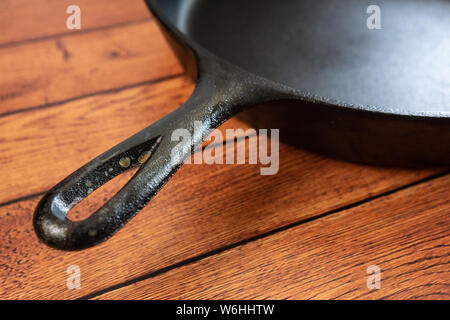 Rusted cast iron skillet handle - rusty culinary problem - downside to this traditional and heavy metal pan on wooden table. Close up of rust. Blank e Stock Photo