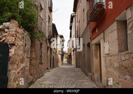 Narrow cobbled street with stone and red-rendered houses in the medieval quarter of Sigüenza, Spain Stock Photo