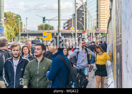 BERLIN, GERMANY - September 26, 2018: A street full of life on a sunny day with tourists and berliners passing by the Berlin Wall at the East Side Stock Photo