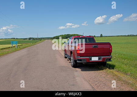 Red pickup truck parked on a rural roadside waiting for rescue or to begin travel in the summer Stock Photo