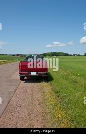Red pickup truck on the side of a rural road pulled over on a journey Stock Photo