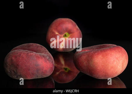 Group of three whole fresh red peach prunus persica platycarpa isolated on black glass Stock Photo