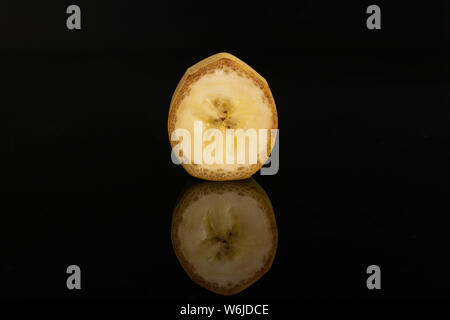 One slice of ripe yellow banana isolated on black glass Stock Photo