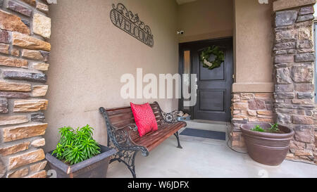 Panorama Home facade with bench welcome sign and potted plants on the porch Stock Photo