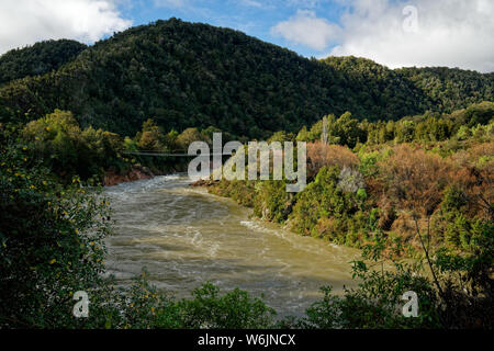 Buller gorge swing bridge over a swollen and muddy Buller river, Buller district, New Zealand. Stock Photo