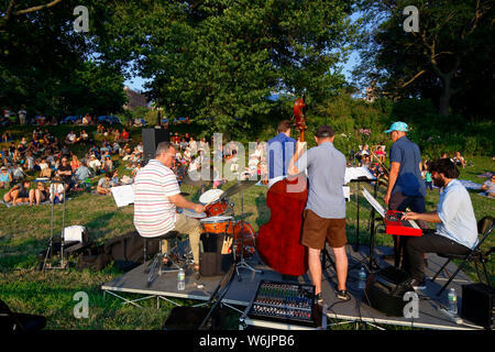 People on the grass listening to live music on a warm summer evening at Riverside Park, New York, NY. (July 27, 2019) Stock Photo