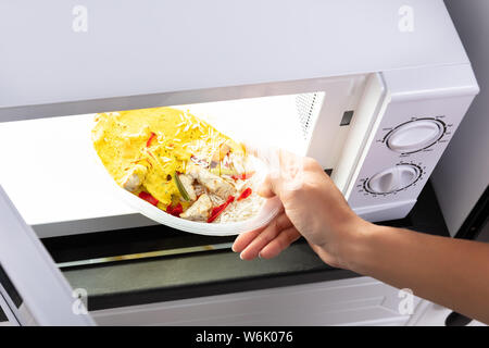 Close-up Of A Person Heating Food In Microwave Oven Stock Photo