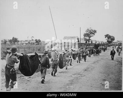 Photograph of American Prisoners Using Improvised Litters to Carry Comrades; Scope and content:  Original caption: This picture, captured from the Japanese, shows American prisoners using improvised litters to carry those of their comrades who, from the lack of food or water on the march from Bataan, fell along the road. Philippines, May 1942. General notes:  According to Colonel Melvin H. Rosen (U.S. Army Retired), this image is not a photograph taken during the Bataan Death March, but rather a photograph of a burial detail at Camp O'Donnell, the terminus of the Death March.  Mr. Rosen is a s Stock Photo