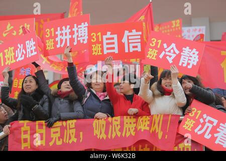 Chinese parents hold banners as their children take part in a mass rally to prepare for the upcoming annual college entrance examination, also known a Stock Photo