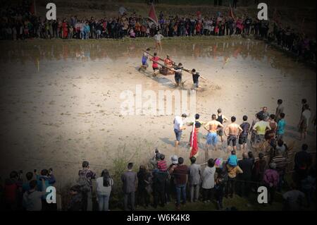 Chinese villagers of the Hakka people carrying a golden statue of ancient Chinese general Guan Gong dash through waterlogged fields during a mud-spatt Stock Photo