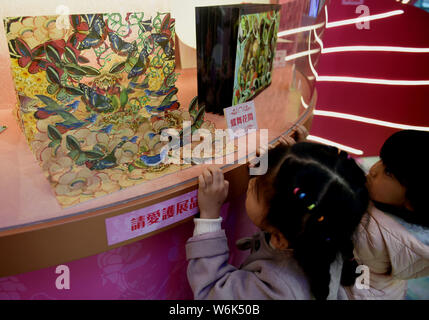 Children enjoy the hand-crafted pop-up 3D paper artworks created by Polish artist and illustrator Bozena Rydlewska on display during the 'New Bot-any' Stock Photo