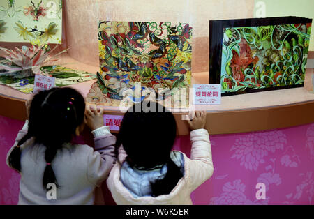 Children enjoy the hand-crafted pop-up 3D paper artworks created by Polish artist and illustrator Bozena Rydlewska on display during the 'New Bot-any' Stock Photo