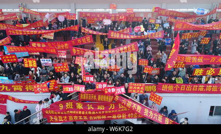 Chinese parents hold banners as their children take part in a mass rally to prepare for the upcoming annual college entrance examination, also known a Stock Photo