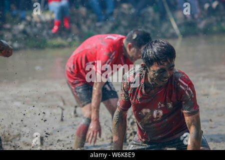 Chinese villagers of the Hakka people carry a golden statue of ancient Chinese general Guan Gong down to waterlogged fields and splash water during a Stock Photo