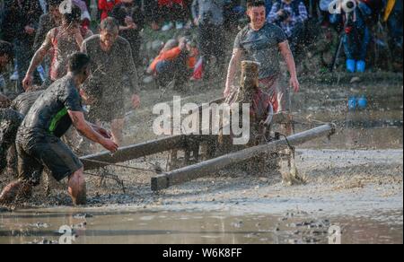 Chinese villagers of the Hakka people carry a golden statue of ancient Chinese general Guan Gong down to waterlogged fields and splash water on the st Stock Photo