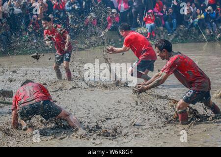 Chinese villagers of the Hakka people carry a golden statue of ancient Chinese general Guan Gong down to waterlogged fields and splash water during a Stock Photo