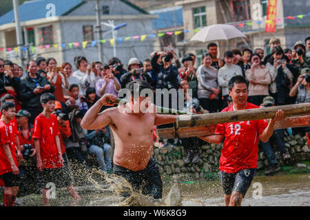 Chinese villagers of the Hakka people carrying a golden statue of ancient Chinese general Guan Gong dash through waterlogged fields during a mud-spatt Stock Photo